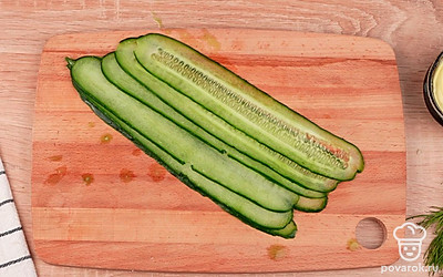 С помощью овощечистки нарежьте огурец тонкими слайсами. Удалите лишний сок огурца бумажными полотенцами.