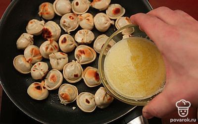 Добавьте в сковороду с пельменями смесь масла и воды, накройте крышкой, убавьте огонь до минимума и томите до готовности.