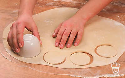 Слепите пельмени. Достаньте тесто из пакета. Засыпьте поверхность стола мукой. Отделите от общего куска тесто размером примерно с кулак и раскатайте толщиной 2-3 мм. Рюмкой вырежьте кружочки диаметром 4-6 см. Положите в центр фарш и хорошо зажмите тесто по краям. Сделайте то же самое с остальными частями теста и фарша.