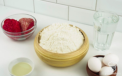 Замесите тесто в миске. Сначала хорошо взбейте яйца с водой, растительным маслом и солью. Муку добавляйте постепенно и постоянно помешивайте. Замесите крутое тесто — чем жестче тесто получится, тем лучше оно будет лепиться. При необходимости достаньте фарш размораживаться.