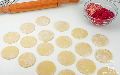 Смешайте свиной и говяжий фарш, добавьте соль и перец по вкусу и мелко порубленный лук. Раскатайте тесто скалкой и вырежте в нем кружочки с помощью стакана.