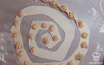 Порции фарша, по 1 чайной ложке, разложите по всей длине полоски теста на расстоянии 2 см друг от друга. Скрепите тесто между кружочками фарша, оставляя середину открытой. Переложите готовые пельмени в кастрюлю с соусом. Предварительно можете разрезать полоску с фаршем на несколько частей, чтобы удобнее было перекладывать. Протушите под крышкой в течение 10 минут.