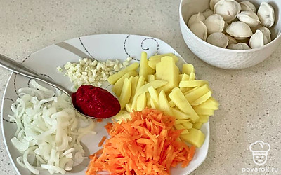 Возьмите овощи, нарежьте соломкой картошку, нарежьте лук полукольцами, измельчите чеснок, натрите на средней терке морковь.
