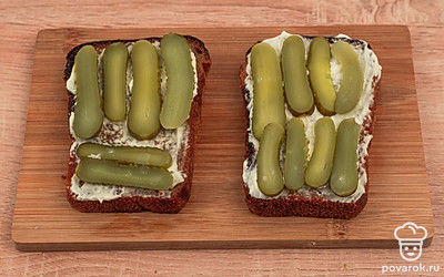 Смажьте гренки чесночным соусом и выложите сверху ломтики огурцов.