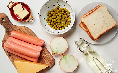 Ломтики хлеба подсушите в тостере или духовке в течение 3 минут. На сосисках сделайте продольные разрезы, сверните их в кольца, соединив концы зубочисткой. Лук репчатый очистите и нарежьте полукольцами. Сыр натрите на мелкой терке. Духовку разогрейте до 180 градусов.