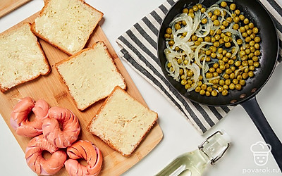 Подготовьте тосты. Каждый ломтик намажьте тонким слоем сливочного масла. На сковороду вылейте подсолнечное масло и потушите репчатый лук и горошек в течение 5 минут.