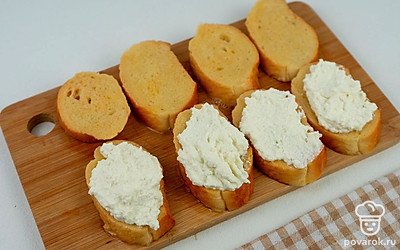 Пропитанные ломтики выложите на ровную поверхность. На четыре из восьми ломтиков выложите творожную начинку и накройте сверху свободным ломтиком багета.