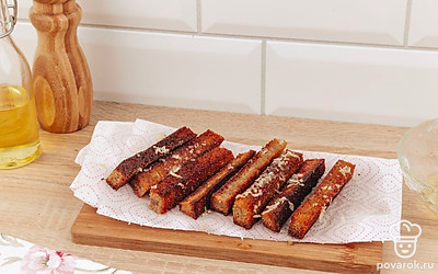 Готовые гренки выложите на бумажные салфетки, чтобы впитались излишки масла, а затем натрите чесночной смесью.