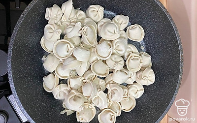 Наливаем в сковороду подсолнечное масло и главный секрет(!) — сразу насыпаем соль и даем ей нагреться. Сверху выкладываем пельмени и накрываем крышкой. Даем подкоптиться около 7-10 минут на среднем огне.