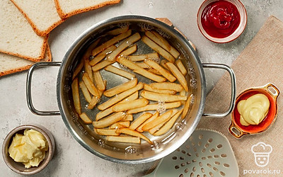 Подготовьте картофель. Нарежьте очищенный картофель тонкой соломкой, посолите по вкусу. В толстодонной кастрюле доведите растительное масло до кипения. В кипящее масло опустите картофель и оставьте его в кастрюле на 3-4 минуты. Достаньте картофель фри при помощи шумовки и положите на бумажное полотенце, чтобы оно впитало лишний жир.