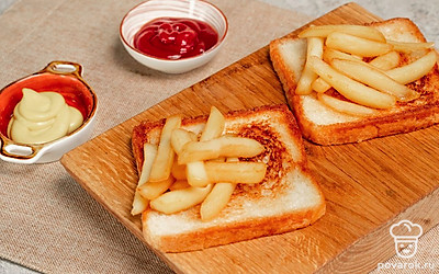 Сделайте тосты. Намажьте сливочным маслом тосты, обжарьте их на разогретой сковороде с обеих сторон. Положите картофель фри на поджаренный тост, украсьте кетчупом и горчицей.