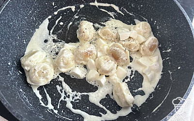 Моцареллу разрежьте на четвертинки. Добавьте к пельменям. Посолите и поперчите по вкусу. Закройте крышкой, томите на медленном огне в течение 3 минут.