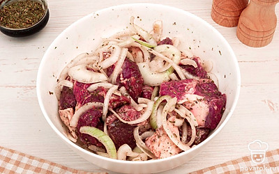 Выложите кусочки баранины в глубокую миску. Добавьте лук, специи и соль. Перемешайте и оставьте мариноваться на 1,5 часа.