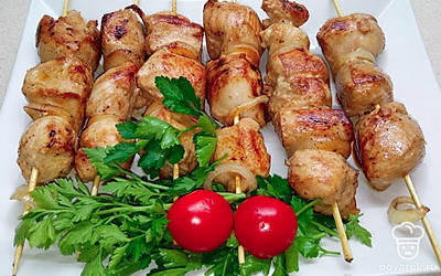 Положите готовый шашлык на тарелку и украсьте зеленью и помидором.