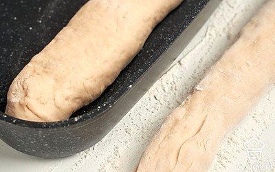 Испеките багеты. Разделите тесто на две части и сформируйте из них продолговатые багеты. Выложите багеты в форму для выпечки, оставьте на 20 минут. Выпекайте багеты в разогретой до 180 градусов духовке в течение 30 минут.