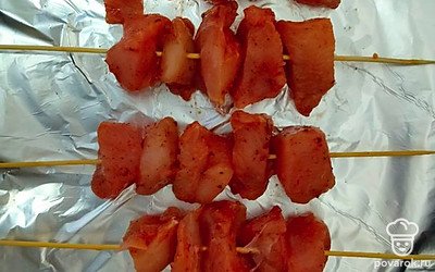 Достать мясо из холодильника, разместить на шпажках. Противень застелить фольгой и выложить на него шашлык.