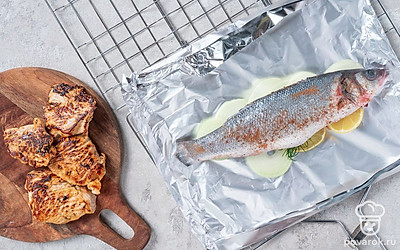 Приготовьте индейку и рыбу на углях. Выложите филе индейки на решетку и жарьте над горящими углями до готовности. Положите сибас на фольгу на подушку из лука, полейте рыбу растительным маслом. Заверните заготовки в фольгу, положите их на решетку и жарьте на углях до готовности.