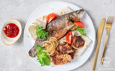 Когда шашлык будет готов, положите кусочки мяса и рыбу на листы лаваша. Подавайте блюдо горячим вместе с томатным соусом и нарезкой из свежих овощей.