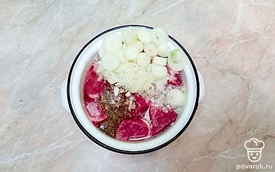 Добавьте к мясу лук, специи (базилик, паприка, тмин, орегано), соль, соевый соус и минеральную воду и аккуратно перемешайте.