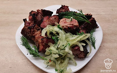 Подавайте шашлык из свиной шейки украсив маринованными луковыми кольцами и ароматной зеленью.
