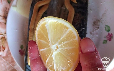 Добавить сок половины лимона. Вторую половину лимона нарезать полукольцами и вложить в брюшко рыбы.