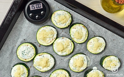 Приготовьте кабачки с йогуртовым соусом. Поверхность каждого кружочка кабачка присыпьте солью и перцем, намажьте соусом. Сверху разместите сырную стружку. Форму для запекания смажьте маслом, разместите кабачки. Готовьте при 180 градусах в духовке 15-20 минут.