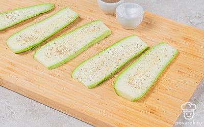 Кабачки нарежьте вдоль тонкими, но не прозрачными, пластинами. Посолите и поперчите.