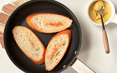 Подсушите багет. Багет нарежьте наискосок на ломтики толщиной 1 см. Подсушите ломтики багета в тостере в течение 1 минуты. Намажьте каждый ломтик тонким слоем горчицы с одной стороны.