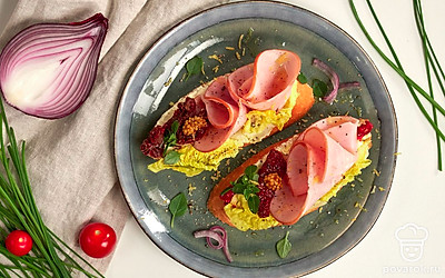 Подавайте багет с копченой свининой, украсив каждую порцию несколькими кусочками вяленых томатов.