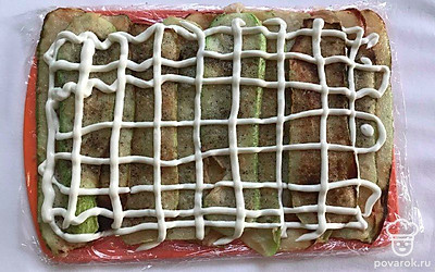 Остывшие кабачки разложите на пищевую пленку внахлест, образуя прямоугольник. Посолите и поперчите их по вкусу и сделайте сетку из майонеза.