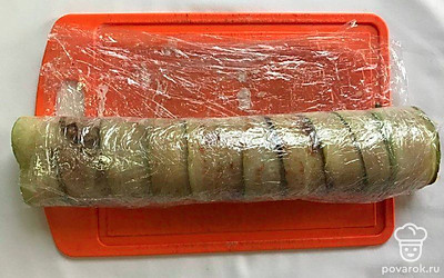 При помощи пищевой пленки скрутите плотный рулет и отправьте в холодильник на 3 часа. Спустя время достаньте рулет из холодильника и освободите его от пищевой пленки. Разрежьте на порционные кусочки.