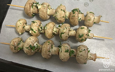 Шпажки заранее замочите в холодной воде на 1 час. Шампиньоны нанижите на шпажки. Выложите на противень, застеленный пергаментной бумагой. Отправьте в разогретую духовку на 20 минут при 180 градусах.