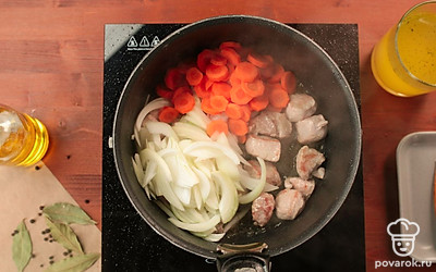 Лук нарежьте тонкой соломкой, морковь — кружочками. Добавьте к свинине, обжаривайте все вместе в течение 10 минут до золотистой корочки.