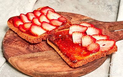 Соберите тосты. Намажьте на хлеб вареное сгущенное молоко. Поверх выложите ломтики клубники.