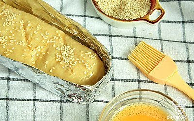 Поставьте багеты выпекаться. Уложите подготовленное тесто в форму, загните выступающие края фольги, после чего накройте будущие багеты пленкой и оставьте их на 30 минут. За 10 минут до истечения времени включите духовку разогреваться до 180 градусов. Когда тесто подойдет, сделайте на нем косые надрезы. Яйцо смешайте с 1 ст. л. воды, щепоткой соли и сахара, смажьте смесью тесто. Посыпьте багеты кунжутом и поставьте в духовку на 40 минут.