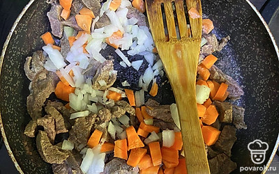 Когда мясо протушится 50 минут, слейте из сковороды лишнюю жидкость. Добавьте подсолнечное масло и лук с морковью. Посолите и поперчите по вкусу. Обжаривайте все вместе 10 минут на среднем огне.