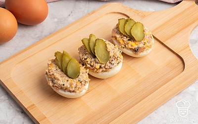 Полученную смесь выложите в готовые половинки яичного белка. Сверху выложите маринованные огурчики.