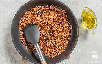 Сковороду с растительным маслом поместите на огонь. Всыпьте в нее гречневую крупу и перемешайте. Обжаривайте гречку на небольшом огне в течение 2-3 минут, пока она не подрумянится и не станет ароматной. Постоянно помешивайте. По истечении времени снимите с огня.