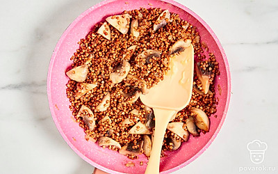 Когда шампиньоны и лук будут готовы, добавьте промытую гречневую крупу. Перемешайте, подержите гречку на огне 2-3 минуты, а затем уберите сковороду с плиты.