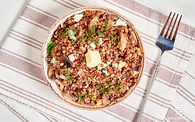 Разложите гречневую кашу по тарелкам. Дополните ее кусочком сливочного масла и подайте на стол.