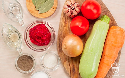 Помойте овощи. Очистите от кожуры морковь, лук, чеснок. Порежьте крупными кусочками лук и морковь. Измельчите чеснок в прессе. Порежьте кабачок кубиками. Подготовьте и простерилизуйте банки и крышки для консервации. Отварите гречку в подсоленной воде, заправьте сливочным маслом. Измельчите в блендере помидоры, шкурку удалите.