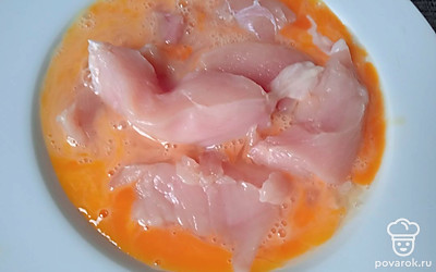 Обваляйте куски индейки в яйцах.