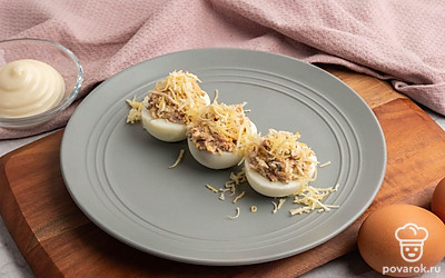 Фаршированные яйца шпротами и сыром выложите на тарелку и украсьте на свой вкус тертым сыром. Приятного аппетита!