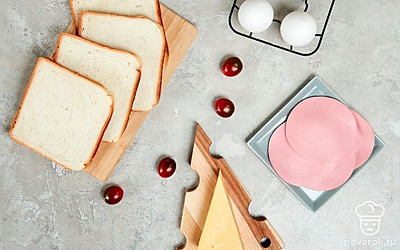 У двух кусочков хлеба вырежьте мякоть, формируя квадратное отверстие. Яйца промойте, просушите. Сыр натрите на мелкой терке. Помидоры черри промойте, удалите плодоножку и разрежьте пополам. Противень застелите пергаментной бумагой. Духовку разогрейте до 180 градусов.