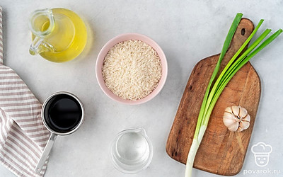 Тщательно промойте рис до прозрачной воды. Вымойте и почистите чеснок. Ополосните и обсушите зеленый лук. Профильтруйте воду и перелейте ее в электрический чайник. Подготовьте сковороду с высокими бортиками и крышкой, а также порционные тарелки.