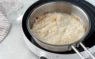 Вскипятите воду в чайнике. Добавьте к чесноку в масло рис и залейте его половиной стакана только что вскипевшей воды.