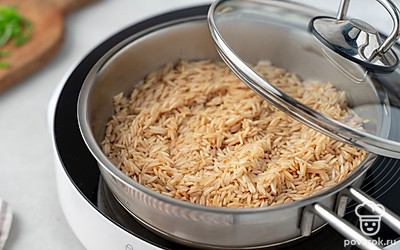 Накройте сковороду крышкой и тушите рис еще около 10 минут до готовности.