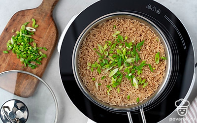 Откройте крышку, всыпьте к рису зеленый лук и перемешайте.