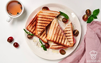 Готовые тосты разрежьте пополам, уложите друг на друга, положите на плоскую тарелку. Рядом разложите черри, украсьте веточкой базилика.