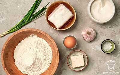 Подготовьте продукты для багета со свиным салом. Воду нагрейте до теплого состояния. Муку просейте. Сало, лук и чеснок нарежьте мелкими кусочками.